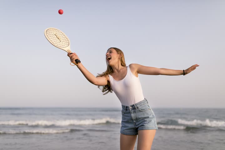 Jogadora de beach tennis rebatendo a bola na praia